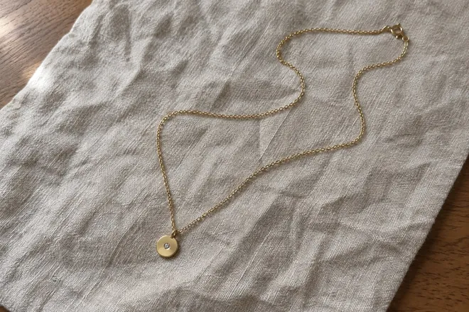 Starting photo: the necklace on crumpled linen on a wooden table