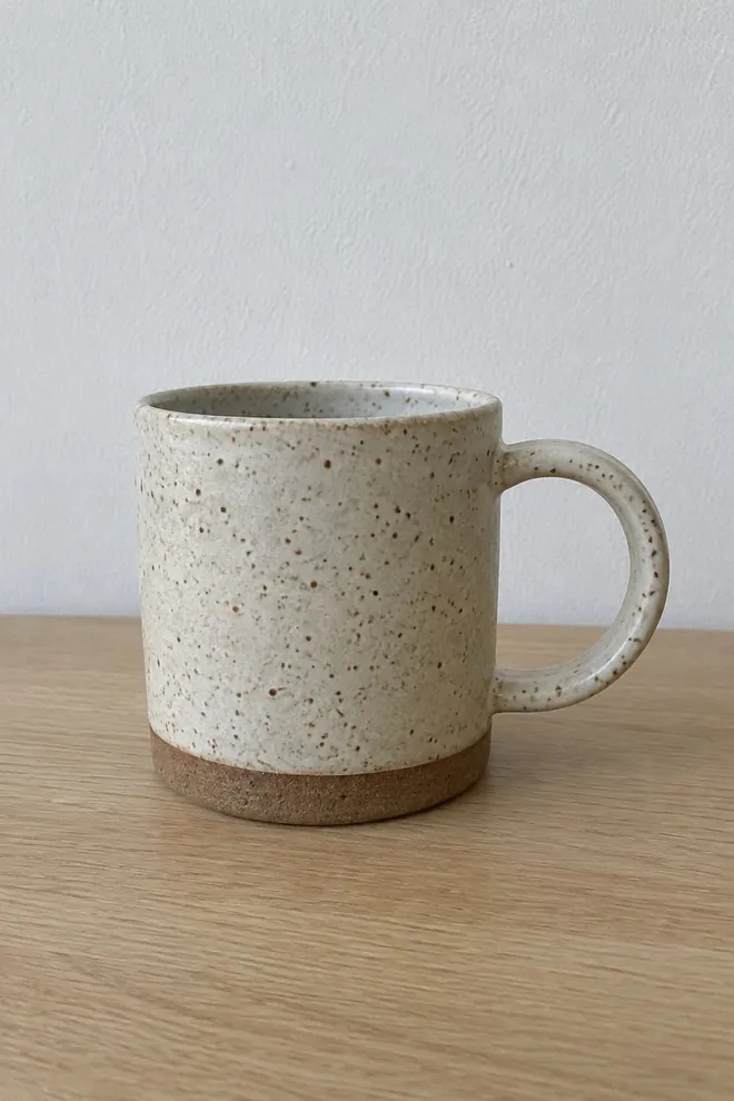 The starting photo, made with AI: a speckled stoneware mug on an oak desk